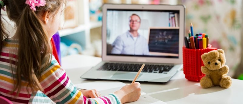young girl looking at laptop through virtual teaching