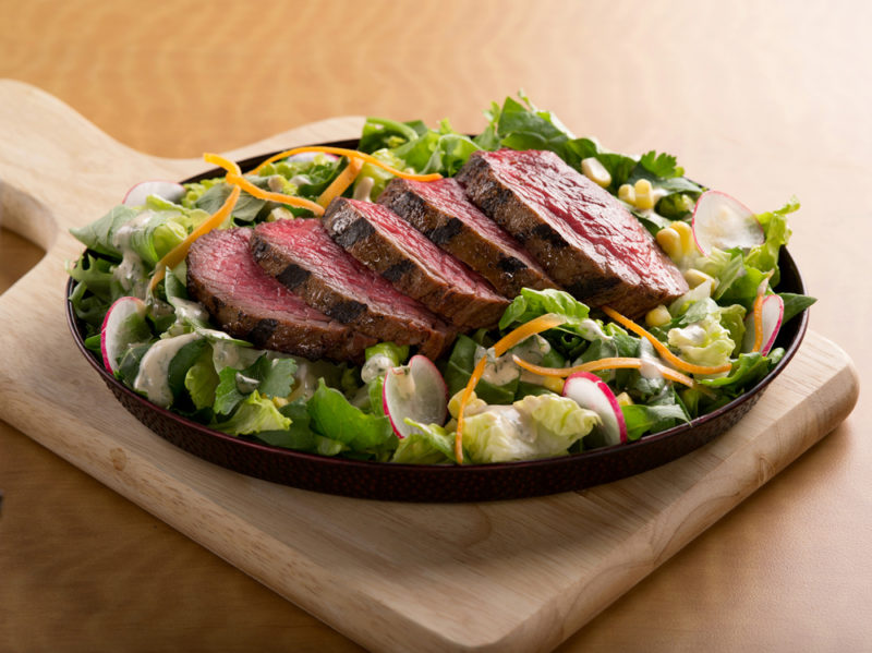 sliced steak on top of salad
