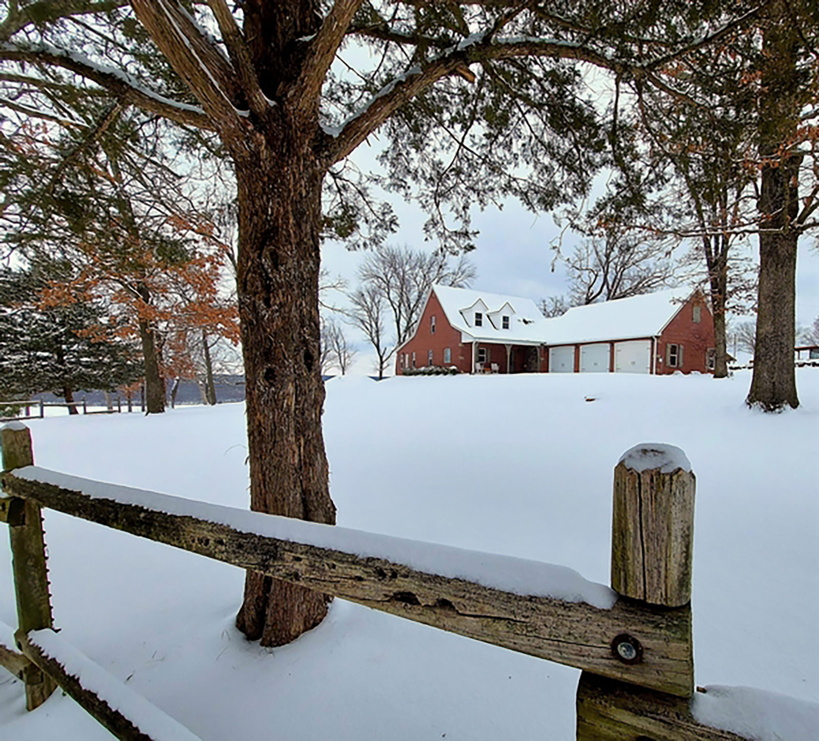 snow covered fence with home in background